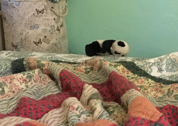 panda balanced on bedframe